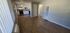 A room with hardwood floors featuring kitchen with white cabinets, stove and sink