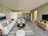 Fully furnished living room with black and white stripped rug, matching throw pillows, white couch, and mounted large screen TV