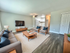 A large furnished living room with grey couch and gray accent chairs, blue throw pillows and mounted TV