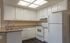 Kitchen with cream-colored walls, white cabinets, and matching white appliances. A wet bar with space for stools is integrated into the design, adding a stylish and functional element to the room