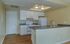 Kitchen with cream-colored walls, white cabinets, and matching white appliances. A wet bar with space for stools is integrated into the design, adding a stylish and functional element to the room
