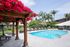 A blue pool surrounded by a gazebo adorned with pink wisteria, creating a serene outdoor space