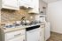 A bright white kitchen featuring a tile backsplash and various decorative elements, creating a clean and inviting atmosphere
