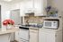 A bright white kitchen featuring a tile backsplash and various decorative elements, creating a clean and inviting atmosphere