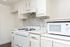 An empty kitchen featuring white cabinetry and vibrant accents, complemented by silver finishes and hardware, creating a fresh and modern space.