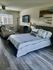 A cozy bedroom featuring a bed, a television mounted on the wall, and a comfortable couch for relaxation.