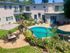 An apartment complex featuring a swimming pool surrounded by patio furniture for relaxation and leisure.