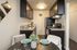 kitchen with dark cabinets, stainless steel appliances, and a dining table set for two with green plates and wine glasses. A small plant serves as a centerpiece.