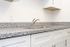 A stylish kitchen with pristine white cabinetry and luxurious granite countertops, creating a sophisticated cooking space.