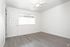 An unoccupied room with elegant hardwood flooring and a ceiling fan, highlighting a clean and minimalist design.
