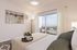 Modern bedroom staging with queen bed looking toward balcony