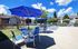 Poolside furniture with table and bright blue umbrella
