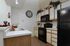Cozy kitchen with white cabinets and wood trim, black appliances, a large wall clock, and decorative greenery. A warm, inviting ambiance.