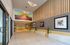 A modern lobby features wood paneling, colorful abstract art, and sleek lighting. The space is open and inviting, with a warm, contemporary feel.