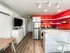 Modern kitchen with bright red accent walls, white cabinets, stainless steel appliances, and wooden flooring. Track lighting creates a cozy atmosphere.
