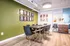 Modern meeting room with a wood table, black chairs, and wall art on green and white walls. Warm lighting creates a welcoming atmosphere.