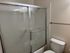 A bathroom featuring a toilet, shower, and sink, with neutral-colored walls and tiled flooring.