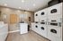 Modern laundry room with ample stacked dryers and washing machines, sleek flooring, and bright lighting for a convenient apartment amenity.
