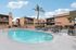 Inviting apartment complex with a sparkling outdoor pool, surrounded by stylish lounge chairs and sun umbrellas, perfect for relaxation and social gatherings.