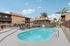 Inviting outdoor pool area with sun loungers, umbrellas, and lush palm trees in a modern apartment complex.