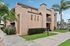 Charming apartment facade with modern design, lush green palm trees, and manicured landscaping in a sunny neighborhood.