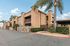 Charming apartment complex with modern architecture and lush palm trees under a clear blue sky.