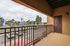 Inviting apartment balcony with stylish railing overlooking a vibrant street view with palm trees and parked cars.