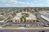 Aerial view of a modern apartment complex with landscaped courtyards, surrounded by a vibrant neighborhood and abundant parking space.