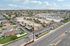 Aerial view of a vibrant residential neighborhood featuring well-maintained homes, lush green lawns, and convenient amenities. Streets are lined with palm trees, creating a picturesque and inviting community atmosphere.