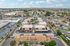 Aerial view of a vibrant residential complex with palm-lined pathways, a sparkling swimming pool, and ample parking, surrounded by a scenic suburban neighborhood.