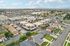 Aerial view of a vibrant neighborhood with modern apartment complexes surrounded by lush greenery and a bustling cityscape in the background.