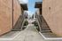 Inviting apartment entrance with dual staircases and lush greenery, offering a warm and welcoming ambiance.