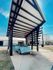 Modern carport with a convertible under clear blue skies, highlighting contemporary architecture.
