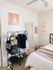 Inviting bedroom with soft decor and neatly organized clothes rack.
