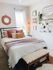 Charming bedroom featuring a comfortable bed with colorful pillows, wall art, and decorative accents, creating a warm and inviting space.