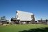 Charming modern building with a steep roof and patio space, set against a vibrant blue sky.