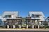 Twin modern cottages with metal roofs and inviting front porches set against a clear blue sky.
