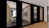 Modern interior office space with elegant glass walls, cozy seating, and a wall-mounted screen.