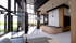 Modern open-concept living space with high ceilings, large windows, and cozy seating area. Features stylish wood accents and elegant staircase.