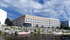 Modern waterfront building with sleek design, surrounded by lush greenery and boating access.