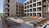 Modern apartment building featuring a stylish outdoor pool area with comfortable lounge chairs and seating, surrounded by contemporary architecture.
