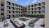 Modern apartment complex with a stylish outdoor pool area, featuring luxurious lounge seating and vibrant greenery.