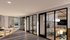 Modern office space with sleek glass partitions, cozy seating area, and natural light streaming through large windows.