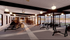 Modern fitness center with sleek design, featuring rowing machines, stationary bikes, and free weights, complemented by ambient lighting and large windows.