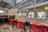 Modern communal area with vibrant red chairs, stylish industrial design, and expansive floor-to-ceiling windows offering a bright and inviting atmosphere.