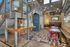 Contemporary industrial-style interior featuring a metal staircase, modern lighting, and vibrant red chairs in a versatile open space.
