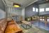 Modern industrial loft space featuring a cozy leather sofa, chic green armchairs, and a sleek metal dining set illuminated by natural light.