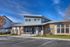 Modern clubhouse exterior featuring sleek architecture with a gable roof and large windows, set against a vibrant blue sky.