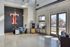Modern office space with high ceilings, chic furniture, and ample natural light from large windows, featuring a bold wall logo and contemporary decor.