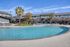 Inviting apartment complex featuring a sparkling swimming pool, surrounded by palm trees and modern amenities.